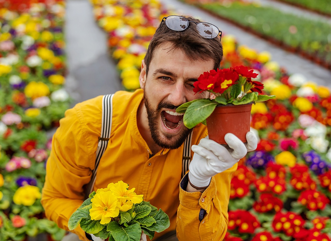 Business Insurance - Excited Man Holds Up Flowers in a Flower Shop