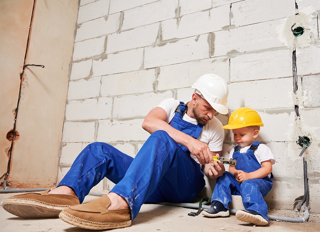 Insurance by Industry - Construction Worker and Baby Dressed at a Construction Worker Use a Tape Measure Together